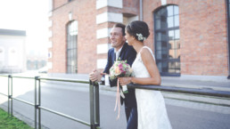 Brautpaar stehen am Geländer und freuen sich