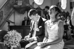 Brautpaar sitzt lachend vor dem Traualtar