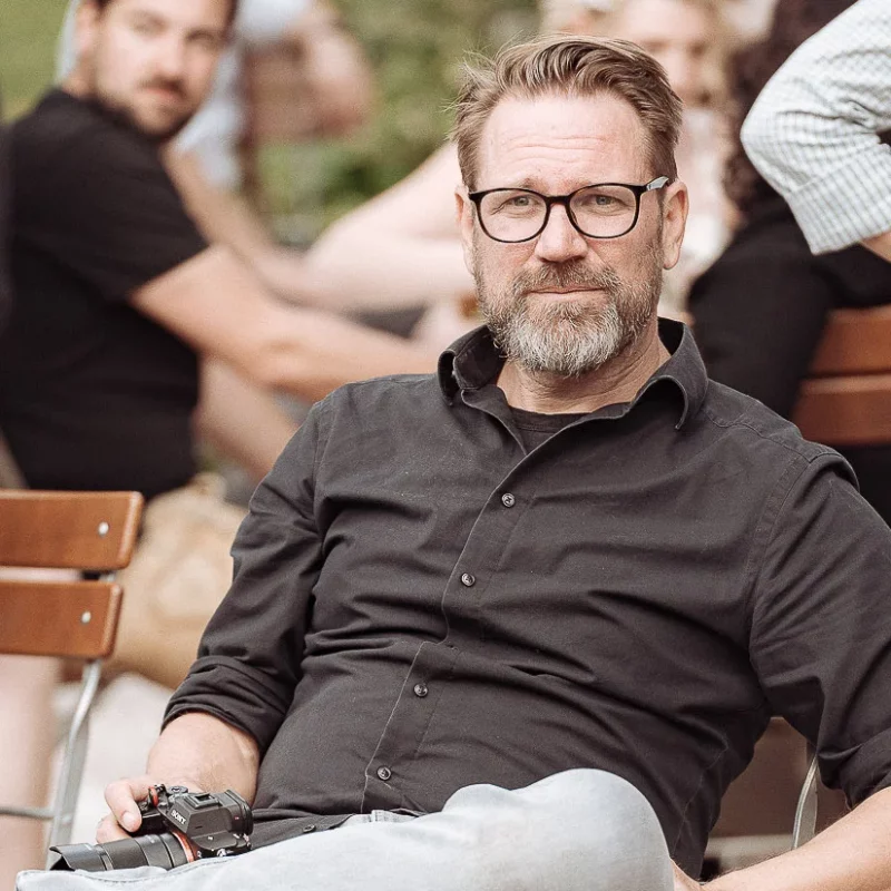 Hochzeitsfotograf Thorsten mit Kamera bei einer Hochzeitsfeier in Rosenheim, umgeben von Gästen im Freien